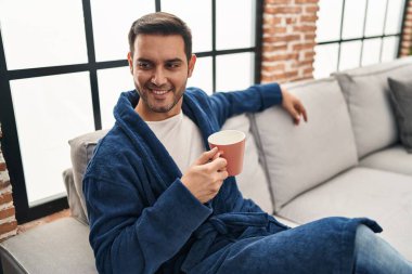 Evde kahve içen bornoz giyen genç bir İspanyol.