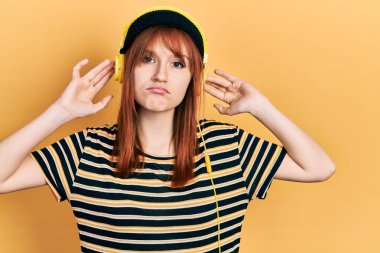 Kızıl saçlı, müzik dinleyen, kulaklık takan, kederli, sinirli ve korkmuş bir genç kadın. hüzünlü ifade. 