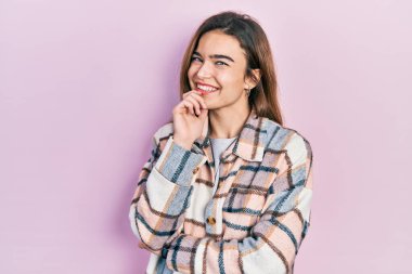 Gündelik kıyafetler giyen genç beyaz kız kameraya kendinden emin bakıyor kollarını kavuşturmuş ve çenesini kaldırmış gülümsüyor. Olumlu düşünmek. 