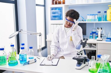 African american woman wearing scientist uniform stressed working at laboratory