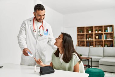 Klinikteki Latin kadına glikoz ölçümü yapan doktor.