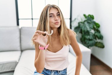 Görünmez hizada duran genç sarışın kadın kameraya bakıyor. Havada öpücük yolluyor. Sevimli ve seksi. aşk ifadesi. 