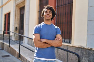 Sokakta kollarını kavuşturmuş İspanyol genç bir adam.