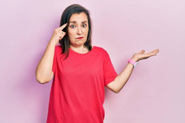 Orta yaşlı İspanyol kadın gündelik kıyafetler giyiyor. Avuç içi açık fotokopi alanı ve alnını göstermekten rahatsız oluyor. Bunu bir düşün.. 