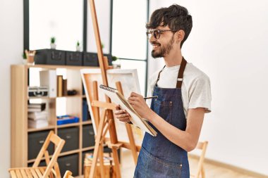 Resim stüdyosunda gülümseyen genç İspanyol sanatçı..