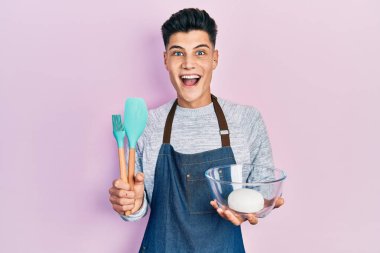İspanyol asıllı genç adam ekmek hamuru ve yemek pişirme aletleri tutuyor çılgın ve başarıyı kutluyor gözleri açık heyecanla haykırıyor. 