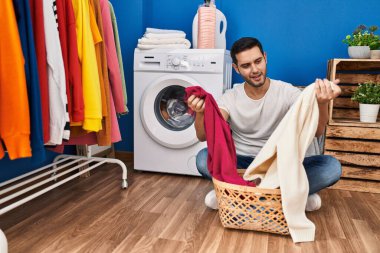 Çamaşır odasında kendine güvenen genç İspanyol adam gülümsüyor.