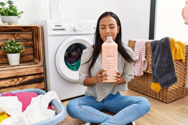 Çamaşır odasında deterjan kokusu alan genç Latin bir kadın.