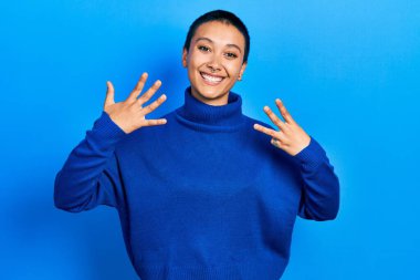 Kısa saçlı, balıkçı yaka kazak giyen güzel İspanyol kadın gülümseyerek kendinden emin ve mutlu bir şekilde parmaklarıyla sekiz numarayı gösteriyor ve işaret ediyor.. 