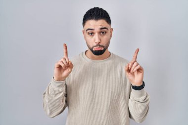 Genç yakışıklı adam, izole edilmiş arka planda dikiliyor üzgün ve üzgün görünüyor, parmaklarıyla yön gösteriyor, mutsuz ve depresif.. 