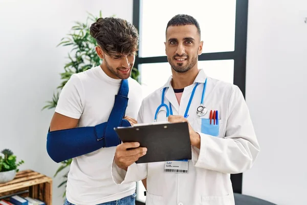 Zwei Hispanische Männer Arzt Und Patient Schreiben Auf Klemmbrett Wartezimmer — Stockfoto