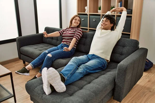 年轻夫妇开心地笑着 坐在家里的沙发上很放松 — 图库照片