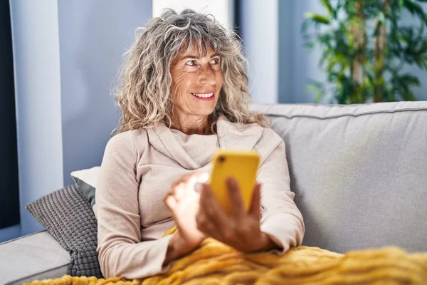 Mujer Mediana Edad Con Teléfono Inteligente Sentado Sofá Casa —  Fotos de Stock