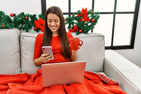 Wanita Latin Muda Menggunakan Smartphone Duduk Dekat Dekorasi Natal Rumah — Stok Foto