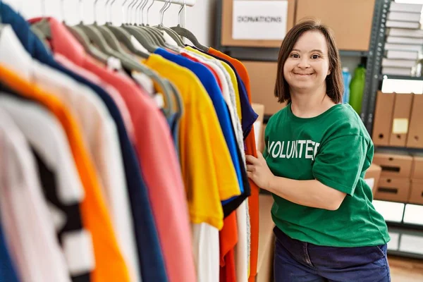 Brunette woman with down syndrome looking at donated clothes at donations stand