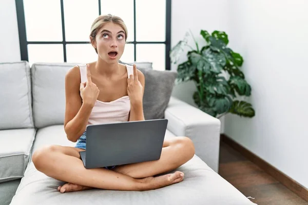Junge Blonde Frau Mit Laptop Hause Sitzt Erstaunt Und Überrascht — Stockfoto