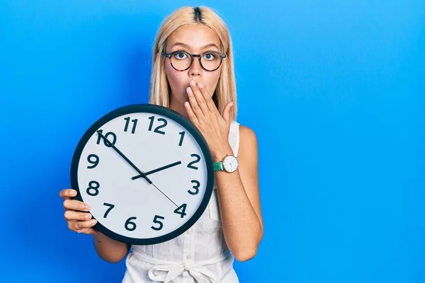 Beautiful Blonde Woman Holding Big Clock Covering Mouth Hand Shocked — Stockfoto