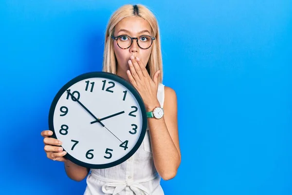 Beautiful Blonde Woman Holding Big Clock Covering Mouth Hand Shocked — Fotografia de Stock