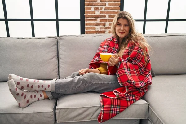 Young Woman Sitting Sofa Drinking Coffee Home Winking Looking Camera — Stockfoto