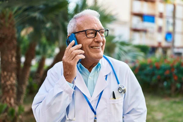 Hombre Mayor Vistiendo Uniforme Médico Hablando Teléfono Inteligente Parque —  Fotos de Stock