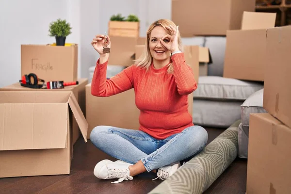 Blonde Woman Holding Keys New Home Sitting Floor Smiling Happy — Stockfoto