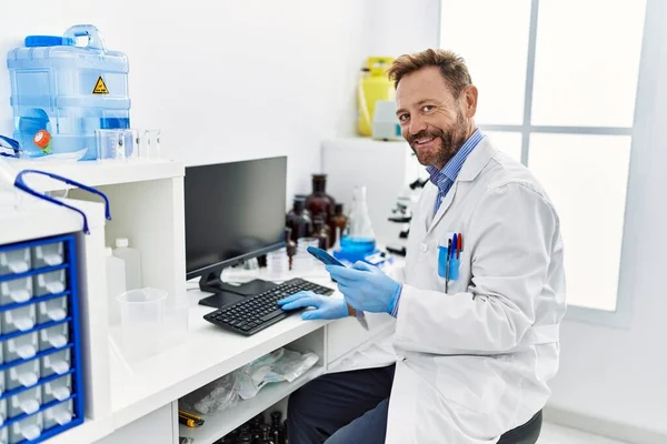 Hispanischer Mann Mittleren Alters Trägt Wissenschaftleruniform Und Benutzt Smartphone Labor — Stockfoto