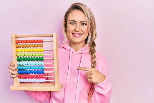 Beautiful Young Blonde Woman Holding Traditional Abacus Smiling Happy Pointing — стоковое фото