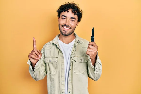 Young Hispanic Man Holding Pocket Knife Surprised Idea Question Pointing — ストック写真