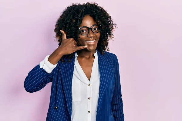 若いアフリカ系アメリカ人の女性がビジネス服を着ていて 眼鏡をかけて電話で話すような手や指で携帯電話のジェスチャーをして笑っている コミュニケーションの概念 — ストック写真
