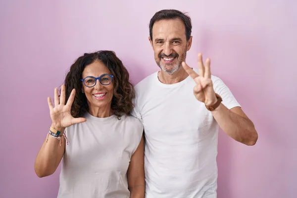Middle Age Hispanic Couple Together Pink Background Showing Pointing Fingers — стоковое фото