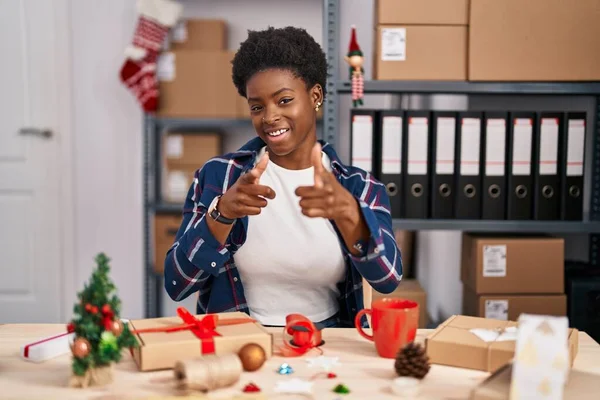 African american woman working at small business doing christmas decoration pointing fingers to camera with happy and funny face. good energy and vibes.