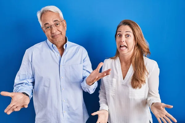 Orta Yaşlı Spanyol Çift Mavi Arka Planda Gülümsüyor Kollarını Açıp — Stok fotoğraf
