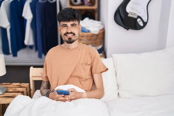 Jonge Spaanse Man Met Behulp Van Smartphone Zitten Bed Slaapkamer — Stockfoto