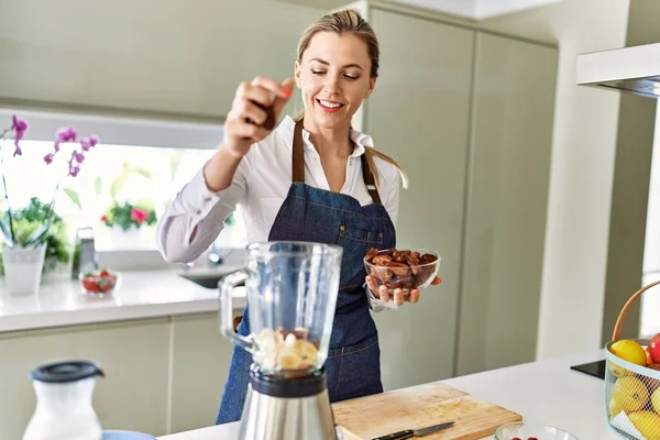 Young Blonde Woman Smiling Confident Pouring Dates Blender Kitchen —  Fotos de Stock