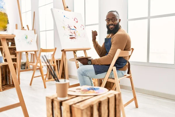 アフリカ系アメリカ人アーティスト男絵画上のキャンバスでアートスタジオ指して親指上に側笑顔で幸せなオープン口 — ストック写真