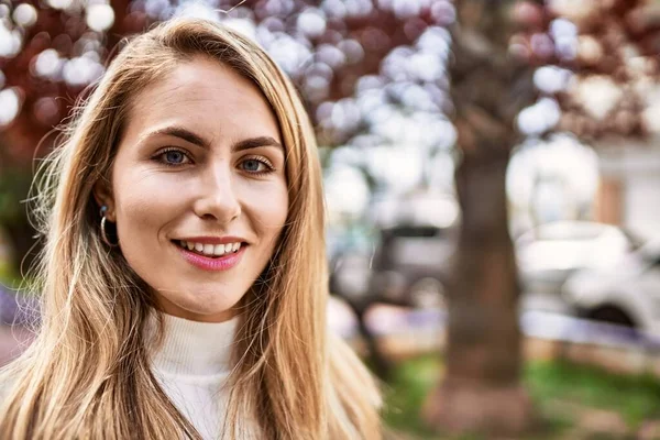 Sokakta kendinden emin gülümseyen genç sarışın kadın