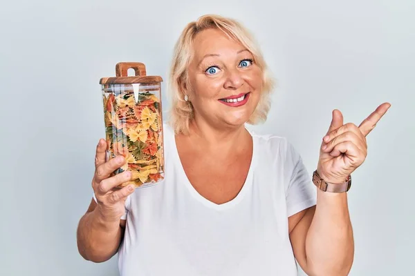 Middle Age Blonde Woman Holding Jar Uncooked Pasta Smiling Happy — Stock Photo, Image