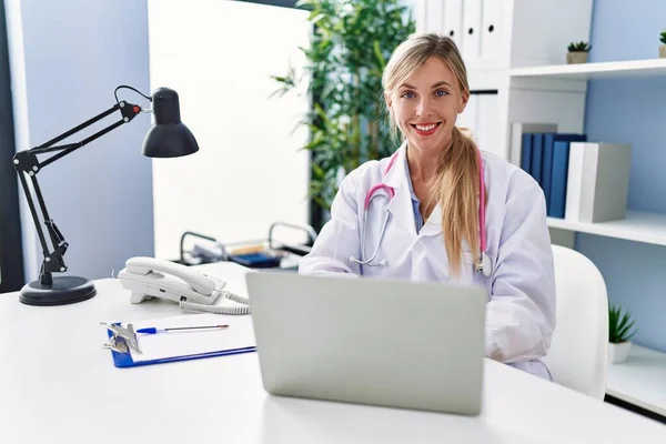 Young Blonde Woman Wearing Doctor Uniform Working Clinic — стоковое фото