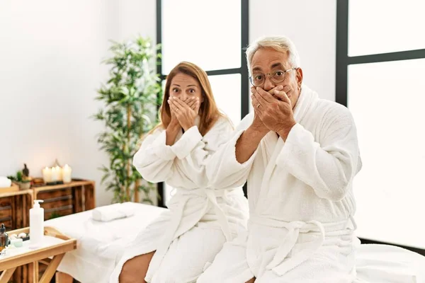 Middle Age Hispanic Couple Wearing Bathrobe Wellness Spa Shocked Covering — Stockfoto