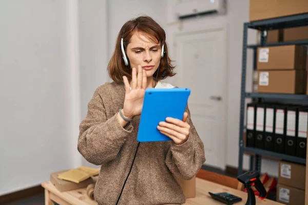 Young beautiful woman working at small business ecommerce with open hand doing stop sign with serious and confident expression, defense gesture