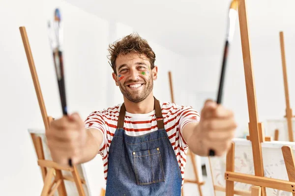 Joven Hombre Hispano Sonriendo Confiado Sosteniendo Pinceles Estudio Arte — Foto de Stock