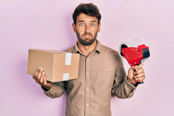 Hombre Guapo Con Barba Sosteniendo Cinta Embalaje Sosteniendo Cartón Deprimido —  Fotos de Stock