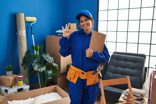 Young Hispanic Technician Working House Renovation Doing Sign Fingers Smiling — Stock Photo, Image