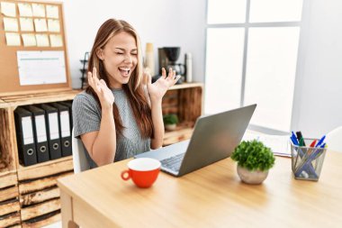 Ofiste çalışan genç esmer kadın dizüstü bilgisayarla başarıyı kutluyor. Kolları havada ve gözleri kapalı heyecanla bağırıyor. Kazanan konsept 