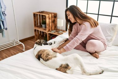 Yatakta köpekle oynarken kendine güvenen genç bir kadın.