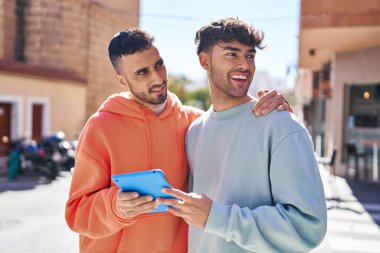 İki erkek caddede birbirlerine dokunarak sarılıyorlar.