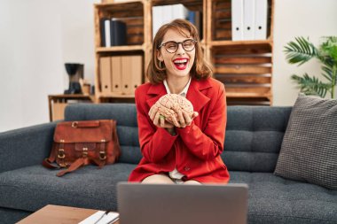 Muayenehanedeki genç esmer kadın beyni tutuyor. Pozitif ve mutlu görünüyor. Kendine güvenen bir gülümsemeyle dişlerini gösteriyor. 