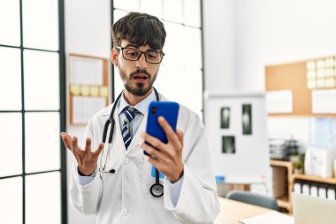 Genç İspanyol doktor, klinikte akıllı telefon kullanarak görüntülü görüşme yapıyor.