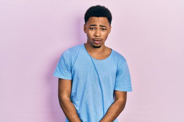 Genç Afro-Amerikalı bir adam günlük mavi tişört giyiyor. Depresyonda ve endişe içinde. Kızgın ve korkmuş. hüzünlü ifade. 