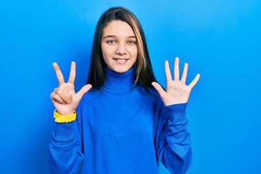 Balıkçı yaka kazak giyen genç esmer kız sekiz numaralı parmaklarını gösterip işaret ederken kendinden emin ve mutlu bir şekilde gülümsüyor.. 